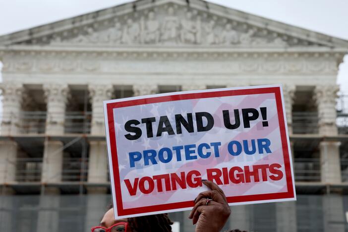A member of Delta Sigma Theta sorority holds up a sign saying "STAND UP! PROTECT OUR VOTING RIGHTS" outside the U.S. Supreme Court on Monday in Washington, D.C.
