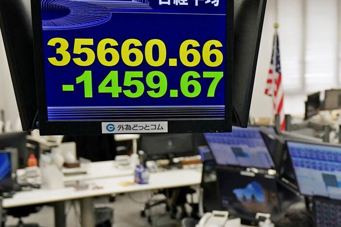 A currency trader works under an electronic stock board at a foreign currency trading firm in Tokyo Monday, March 31, 2025.
