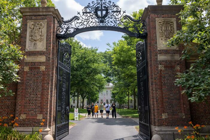 People walk through the gate on Harvard Yard at the Harvard University campus in Cambridge, Mass.