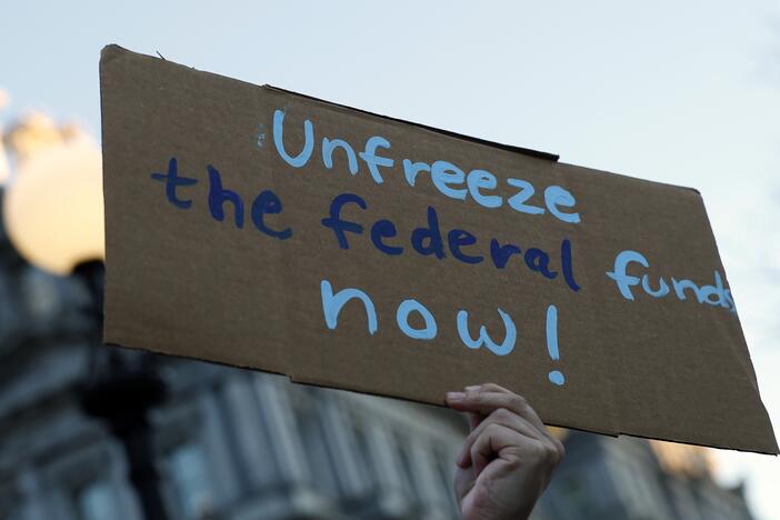 An activist protests against the Trump administration's plan to stop some federal grants and loans during a rally near the White House on January 28 in Washington, DC.
