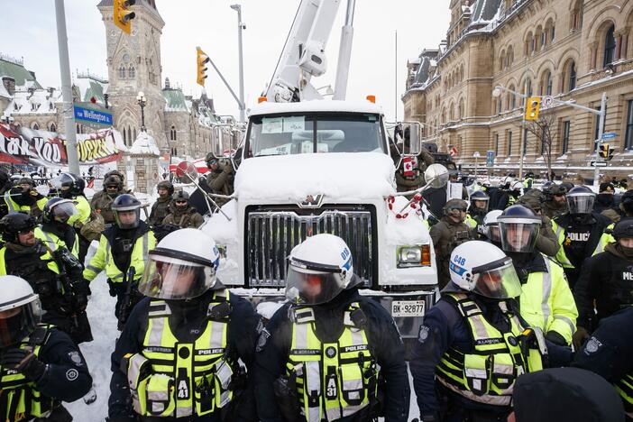 Police hang off a truck as authorities work to end a protest against COVID-19 measures in Ottawa on Feb. 19, 2022.