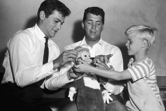 Jay North, young star of the new <em>Dennis the Menace</em> series, right, attempts to handcuff Dean Martin, center, as they play with a stuffed toy with Tony Curtis on Sept. 15, 1959.