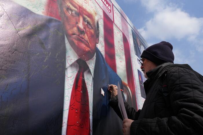 A man writes a slogan on a portrait of the U.S. President Donald Trump during a rally commemorating anniversary of Iran's 1979 Islamic Revolution that toppled the late pro-U.S. Shah Mohammad Reza Pahlavi and brought Islamic clerics to power, in Tehran, Iran, Monday, Feb. 10, 2025. Trump says the US and Iran will have direct nuclear talks soon.