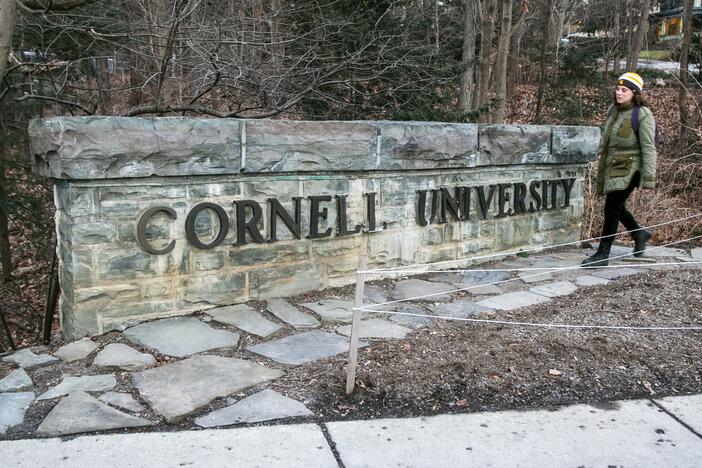 A woman walks by a Cornell University sign on the Ivy League school's campus in Ithaca, New York, on Friday, Jan. 14, 2022.