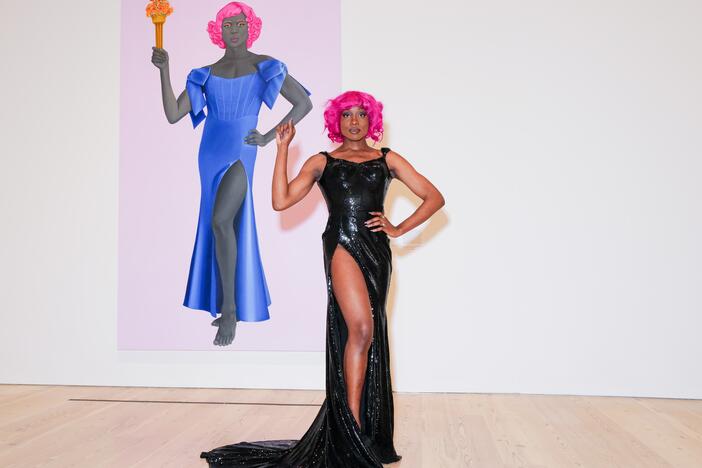 Artist Arewà Basit poses in front of <em>Trans Forming Liberty </em>(2024), a 10-foot oil painting by Amy Sherald.<br>