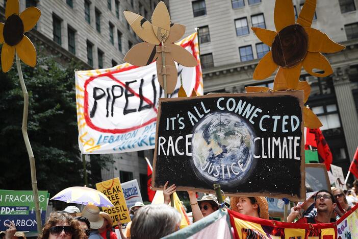 Climate change activists carry signs as they march during a protest in Philadelphia in 2016. Earlier that year, U.S. prosecutors allege hackers began targeting prominent American climate activists in an effort to gather information to foil lawsuits against the fossil fuel industry over damage communities have faced from global warming.<br><br>