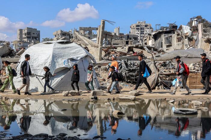 People walk by a tent shelter near the rubble of a collapsed building in western Gaza City on April 15.