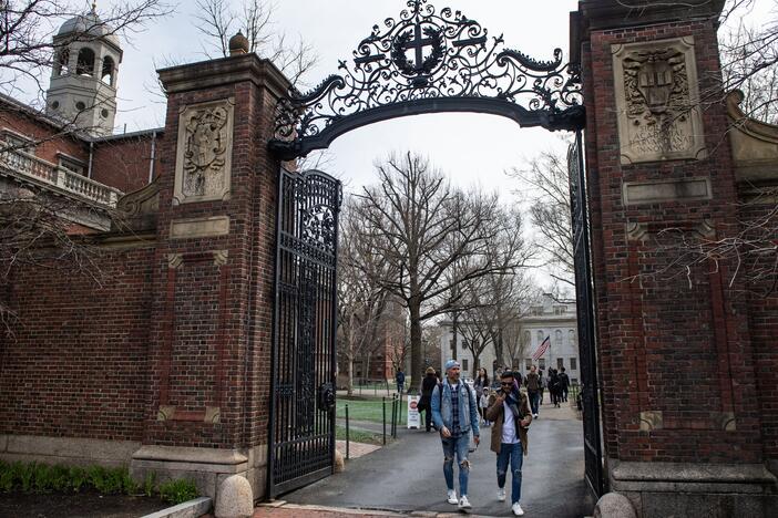 People walk through a gate as they exit Harvard Yard on the campus of Harvard University campus in Cambridge, Massachusetts, on April 15, 2025.