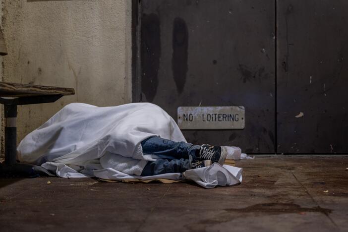 An unhoused resident sleeps on a dimly lit porch on the steps of a school in Austin. This week, all staff  at the United States Interagency Council on Homelessness, which coordinates homelessness policy across the federal government, were put on leave.
