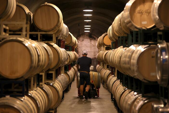A worker pushes a wine barrel into a storage facility at Hunnicutt winery in St. Helena, Calif., on Sept. 30, 2021.