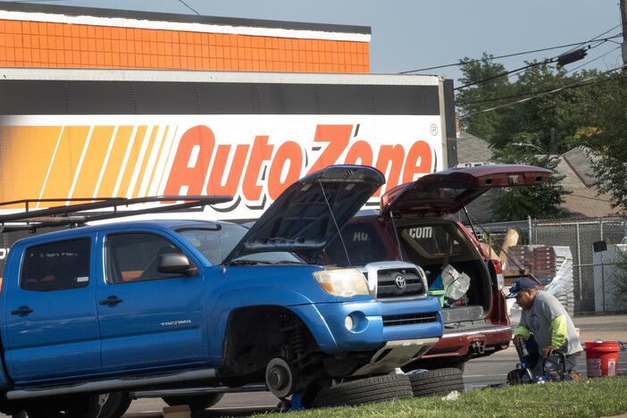 Men repair the brakes on a truck in the parking lot of an auto parts store in Middletown, Ohio, in 2024. Prices of car parts, car repairs and car insurance are expected to rise if tariffs remain in place.