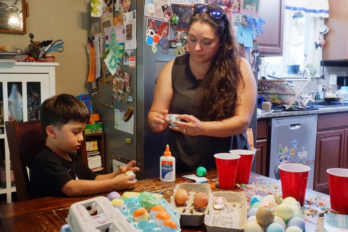 Denise Solis shows her four-year-old son Noah Solis how to seal a cascaron (confetti-filled egg) with tissue paper.