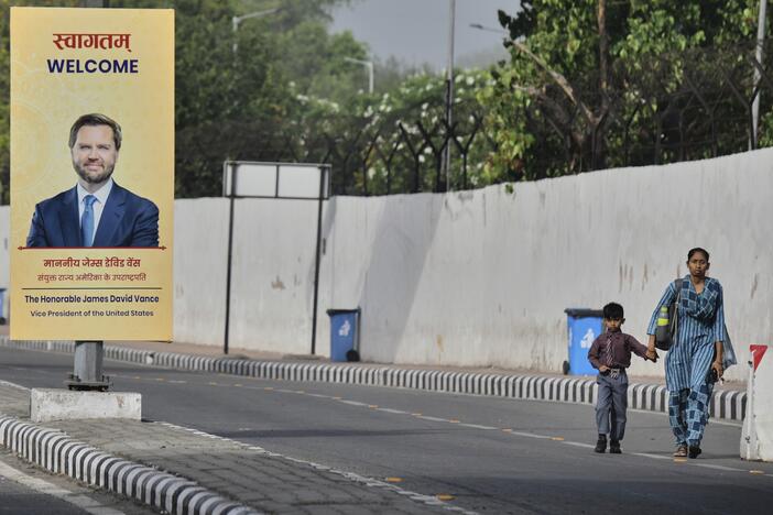 A woman and a child walk past a banner welcoming U.S. Vice President JD Vance on a street in New Delhi, India, on Monday.