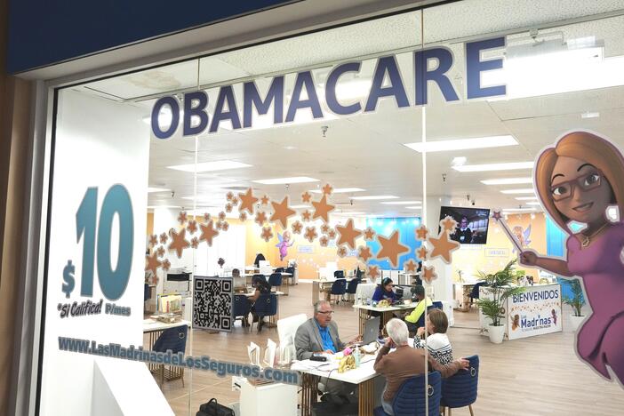 An insurance agent talks with clients inside a shopping center in Miami, on Dec. 5, 2023. Once someone enrolls in an Affordable Care Act plan, they can get help with sticky insurance issues from caseworkers at the federal government. Many caseworkers were cut in the recent round of federal layoffs.