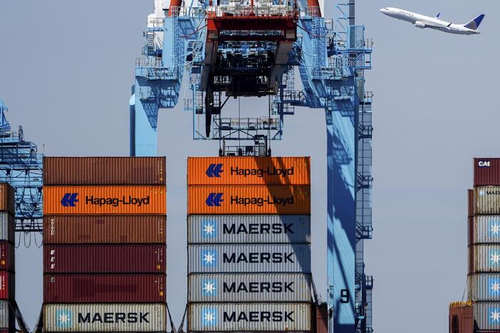 An airplane flies over the container ship Alexandra at the Port Newark Container Terminal on April 18 in Newark, N.J.