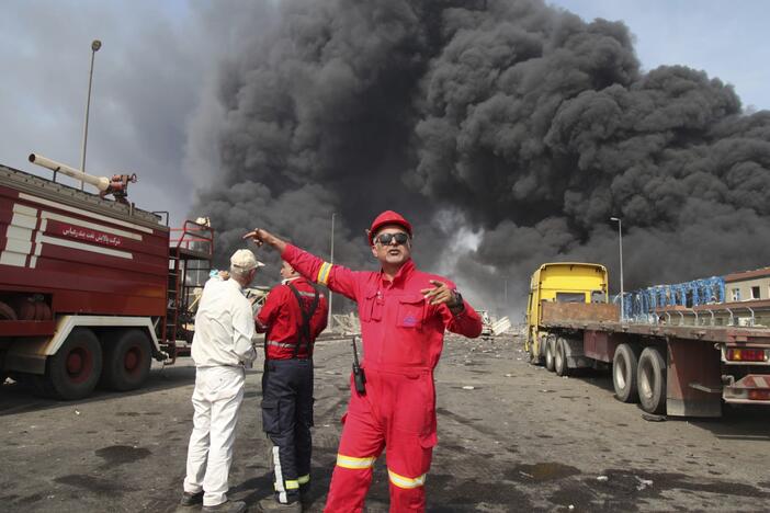 In this photo provided by Islamic Republic News Agency (IRNA), firefighters work as black smoke rises in the sky after a massive explosion rocked a port near the southern city of Bandar Abbas, Iran on Saturday.
