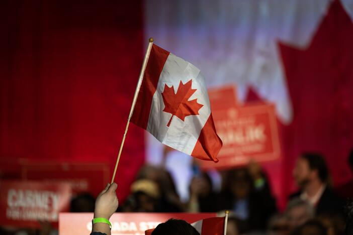 A supporter waves a Canadian flag during a campaign rally for Mark Carney, Canada's prime minister, in Calgary, Alberta, Canada, on Tuesday, April 8, 2025. Carney said Donald Trump's tariff policy is an act of economic self-sabotage that's pushing the US into a downturn. Photographer: Gavin John/Bloomberg via Getty Images