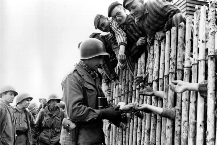 A still from a documentary film shows a U.S. soldier reaching out to outstretched hands of prisoners of the liberated Nazi concentration camp at Dachau, in then West Germany, in April 1945, during World War II.