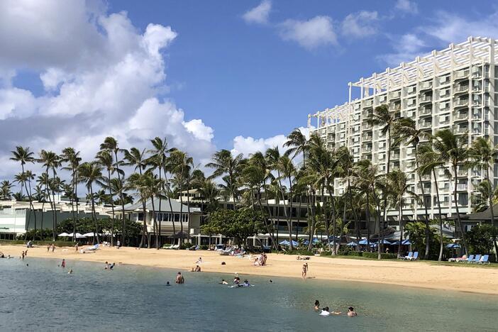 People are seen on the beach and in the water in front of the Kahala Hotel & Resort in Honolulu, Nov. 15, 2020.