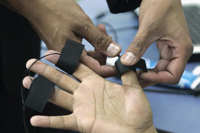 A polygraph examiner applies electrodes on the fingers of a subject in Bogota, Colombia on June 12, 2007.