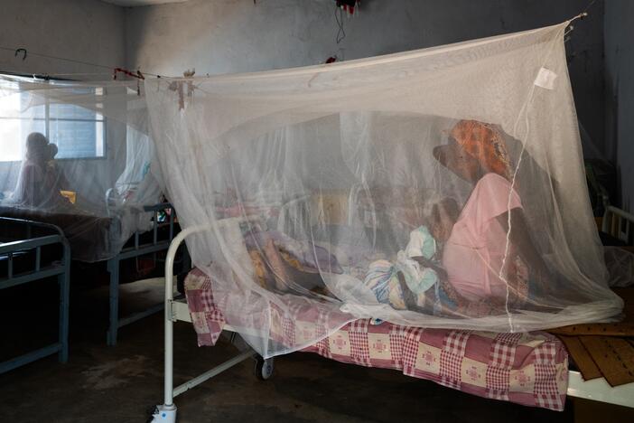 A pregnant woman brought her child to a health clinic in Farchana, Chad. They are sitting under a mosquito net. MIdwives play a critical role in addressing the country's high rate of maternal mortality.