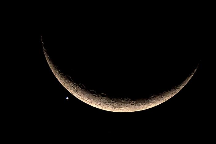 The crescent moon and Venus are pictured in Bangkok in 2023. A failed Soviet lander bound for Venus in 1972 and stranded in orbit is finally set to return to Earth.