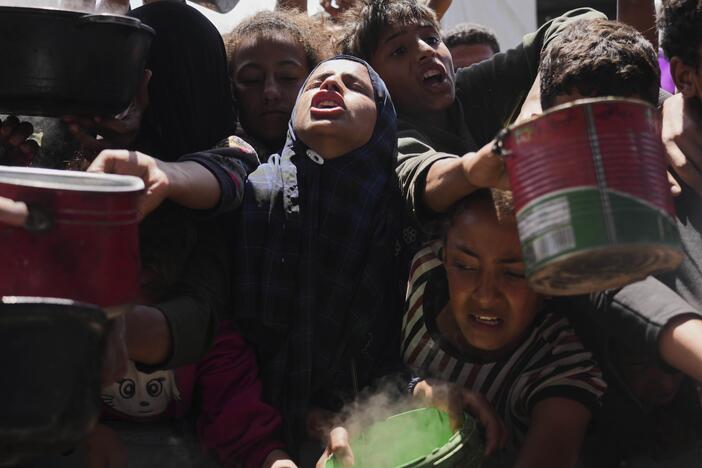 Palestinians struggle to get donated food at a community kitchen in Khan Younis, Gaza Strip, Monday.