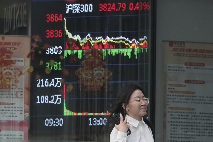 A woman passes by a stock index at a brokerage in Beijing, Wednesday.