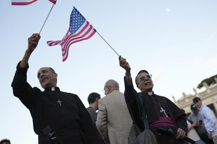 Clerics wave US flags during the speech of the newly elected Pope Leo XIV at the Vatican, Thursday, May 8.