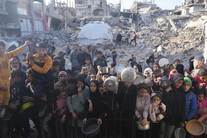 Palestinians wait for donated food at a distribution center in Beit Lahiya, northern Gaza Strip, Sunday, March 16, 2025.