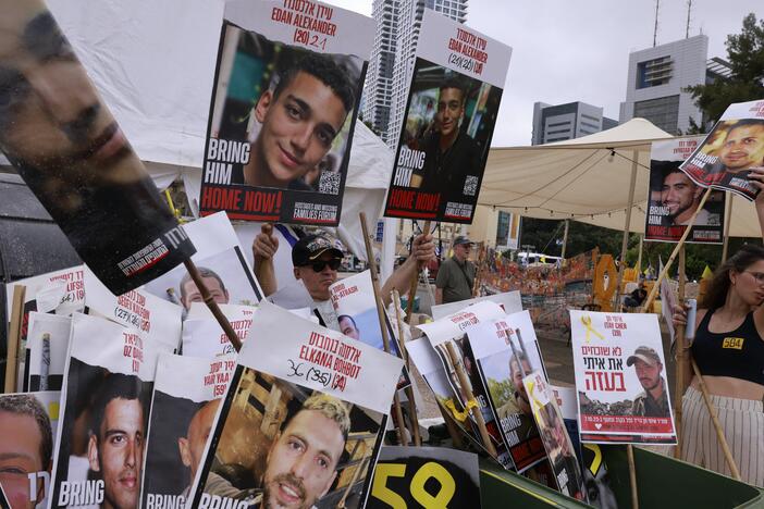 A woman holds a poster bearing a portrait of an Israeli hostage held by Hamas in Gaza since October 2023 next to several portaits, including two (center) of Israeli-U.S. captive Edan Alexander, at Hostages Square in Tel Aviv as people wait for his release on May 12.
