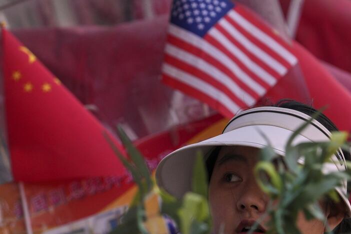 A woman walks past Chinese and United States' national flags on display at a merchandise store in Beijing.