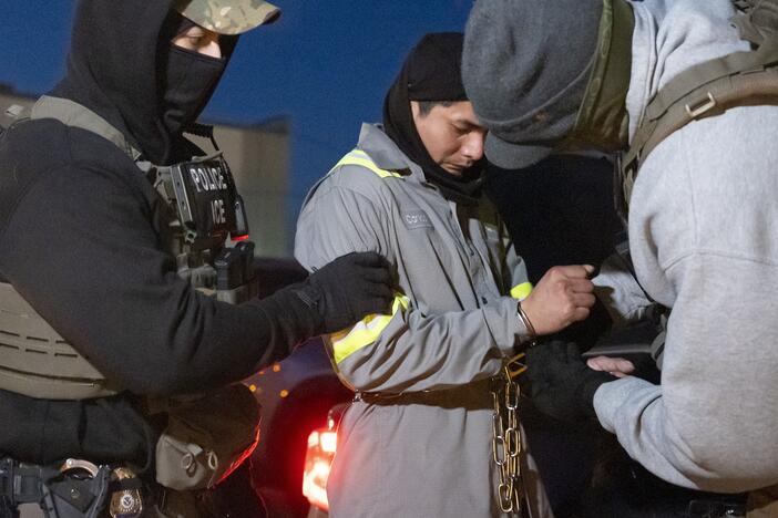 U.S. Immigration and Customs Enforcement officers use a chain to more comfortably restrain a detained person using handcuffs positioned in front.