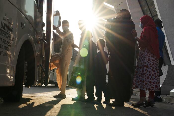 Families evacuated from Kabul, Afghanistan, wait to board a bus after they arrived at Washington Dulles International Airport, in Chantilly, Va., on Aug. 27, 2021.