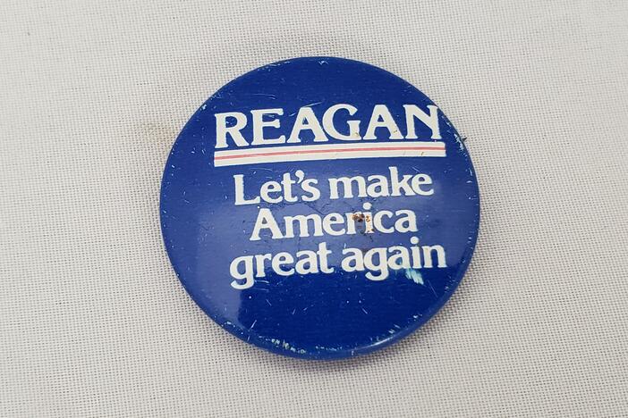 Close-up photo of pinback button with text reading Reagan, Let's Make America Great Again, for Ronald Reagan's 1980 presidential election campaign.