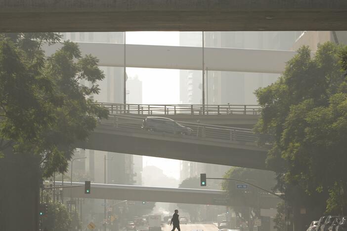 A person crosses a street as smog fills the air Wednesday, Dec. 4, 2024, in Los Angeles.