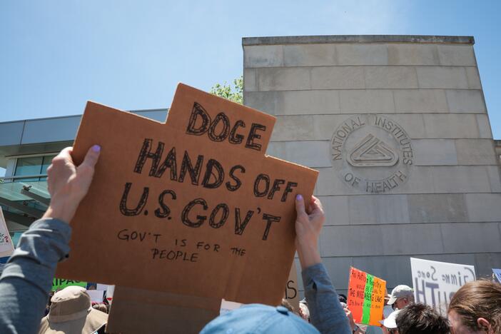 Demonstrators raise signs during a rally outside the National Institutes of Health on May 10 in Bethesda, Md.