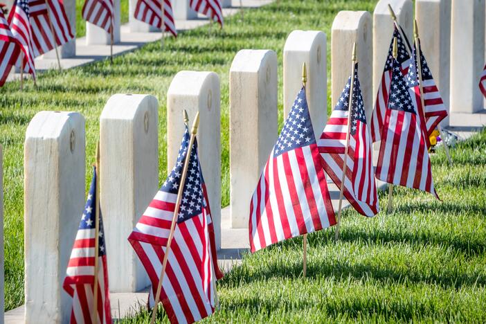 Military headstones honoring armed forces service members are decorated with American flags for Memorial Day.