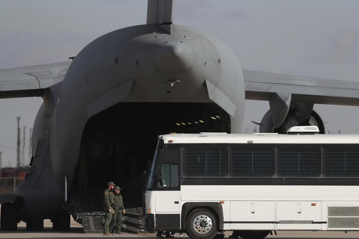 A military aircraft waits for migrants to board from a bus at Fort Bliss in El Paso, Tx., on Jan. 30, 2025, before deporting them to Guatemala.