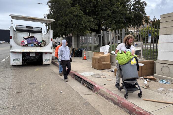 Iraq war veteran Irving Webb moves his belongings as sanitation workers clear the sidewalk, where he spent some nights in April, outside the Los Angeles VA campus.