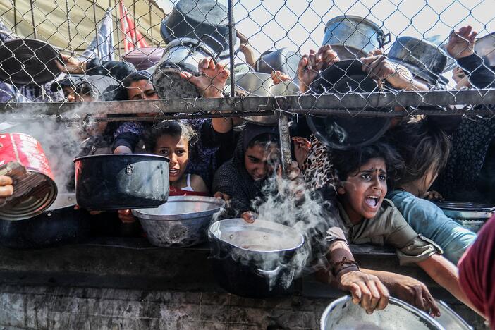 Displaced Palestinians, including women and children living in tents, receive food distributed by aid organizations in al-Mawasi district of Khan Younis, Gaza, on May 30. In Jordan, tens of thousands of boxes of food aid for Gaza are moldering in warehouses.