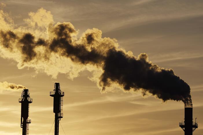 The sun begins to set beyond an oil refinery in California.