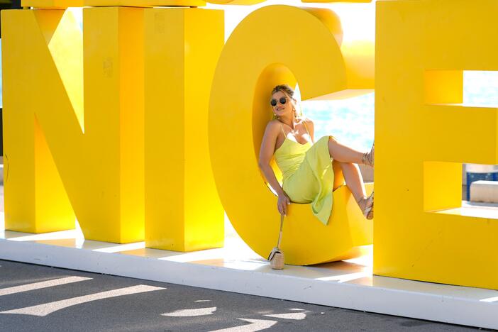 A woman poses for a photo on a sign spelling out the name of Nice, France, last summer. The city's name derives from Nike, the Greek goddess who heralds victory — not the word "nice," which was borrowed into Old French from Latin long after the city was founded.