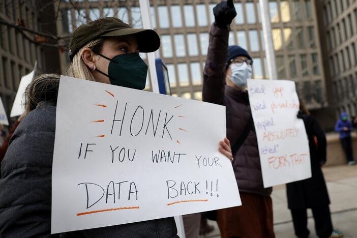 A protester with a sign saying "HONK IF YOU WANT YOUR DATA BACK!!!" stands with other demonstrators outside of the U.S. Office of Personnel Management's headquarters in February in Washington, D.C., to rally against the DOGE team set up by President Trump's billionaire adviser Elon Musk getting access to personal data about federal employees.