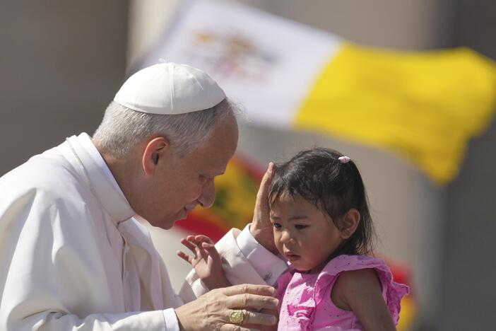Pope Leo XIV caresses a little girl as he arrives to celebrate a Mass for the Jubilee of New Religious Associations on Pentecost Day in St. Peter's Square at the Vatican, Sunday, June 8, 2025.