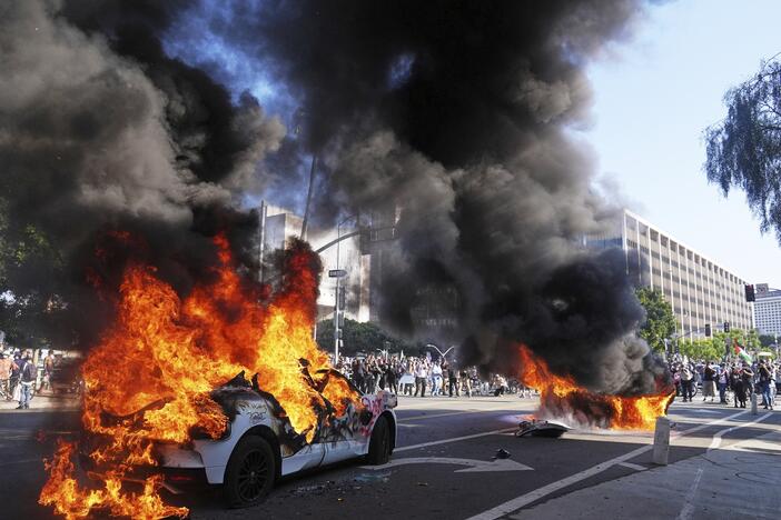 Two Waymo taxis burn near the metropolitan detention center of downtown Los Angeles, Sunday, June 8, 2025, following last night's immigration raid protest.