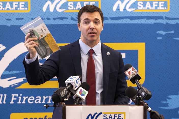 N.C. Attorney General Jeff Jackson holds a gun lock at an event about safe storage of firearms. North Carolina is among 30 states with the most permissive gun laws, according to a new study.