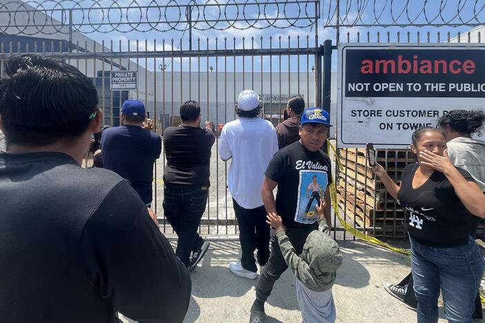 People gather in front of Ambiance Apparel after several employees were taken into custody by federal agents in the Fashion District in downtown Los Angeles on Friday.