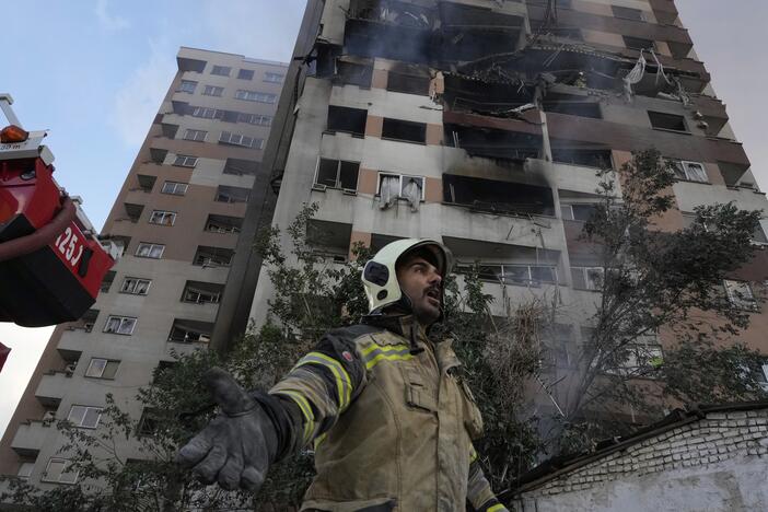 A firefighter calls out his colleagues at the scene of an explosion in a residence compound in northern Tehran, Iran, Friday, June 13, 2025.