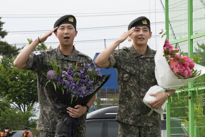 K-pop band BTS members RM, left, and V salute after being discharged from a mandatory military service in Chuncheon, South Korea, on Tuesday.